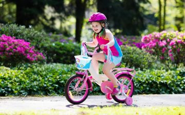 Girl riding a bike with training wheels