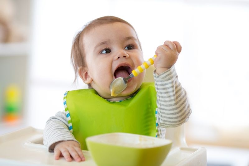 baby eating with a bib