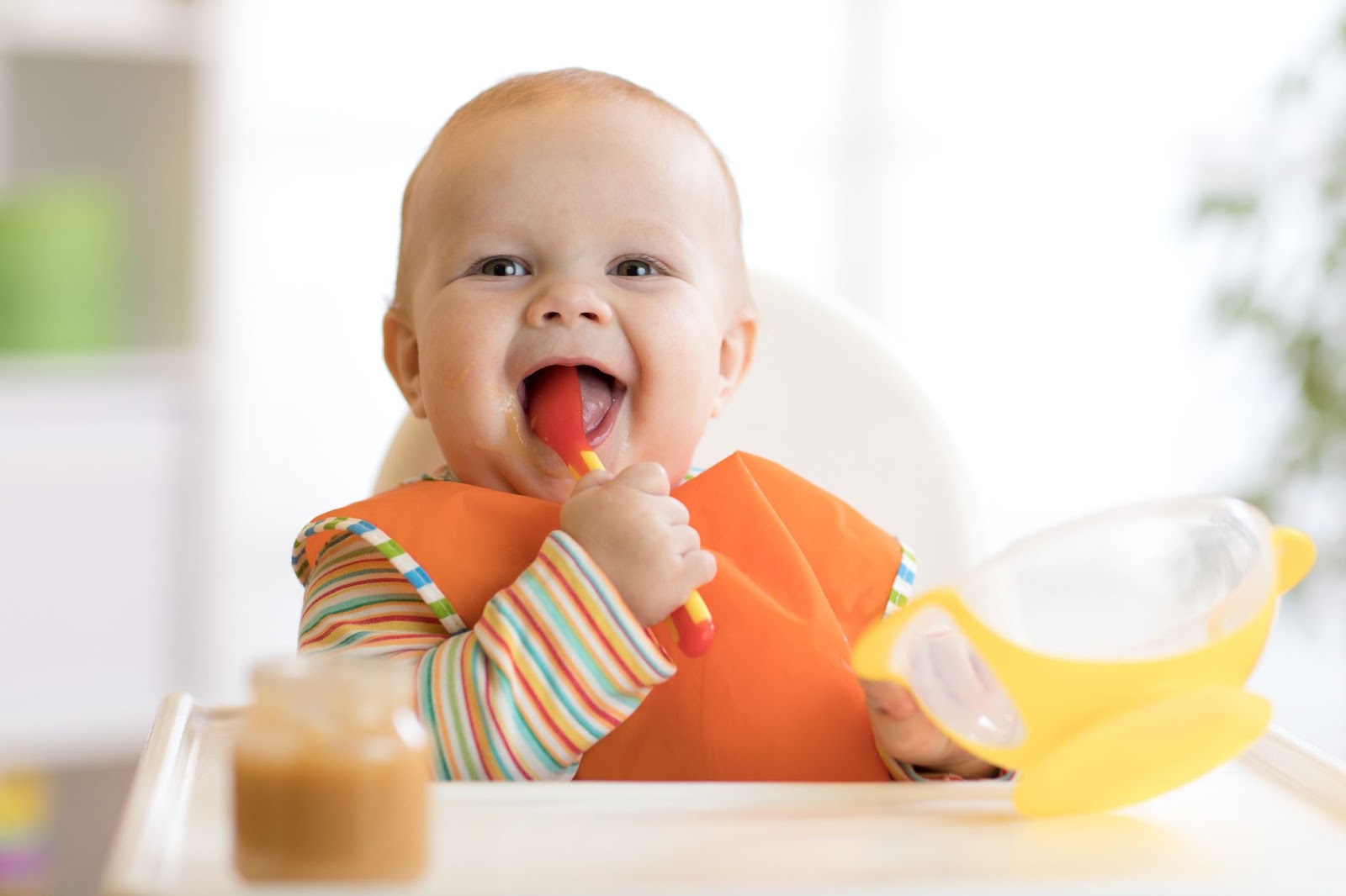 https://www.ashtonbee.com/wp-content/uploads/2021/12/baby-holding-an-orange-spoon-while-eating.jpg