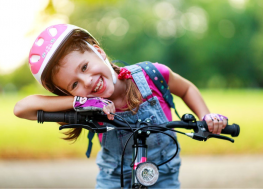 toddler girl bike helmet - girl smiling while on a bike with pink helmet