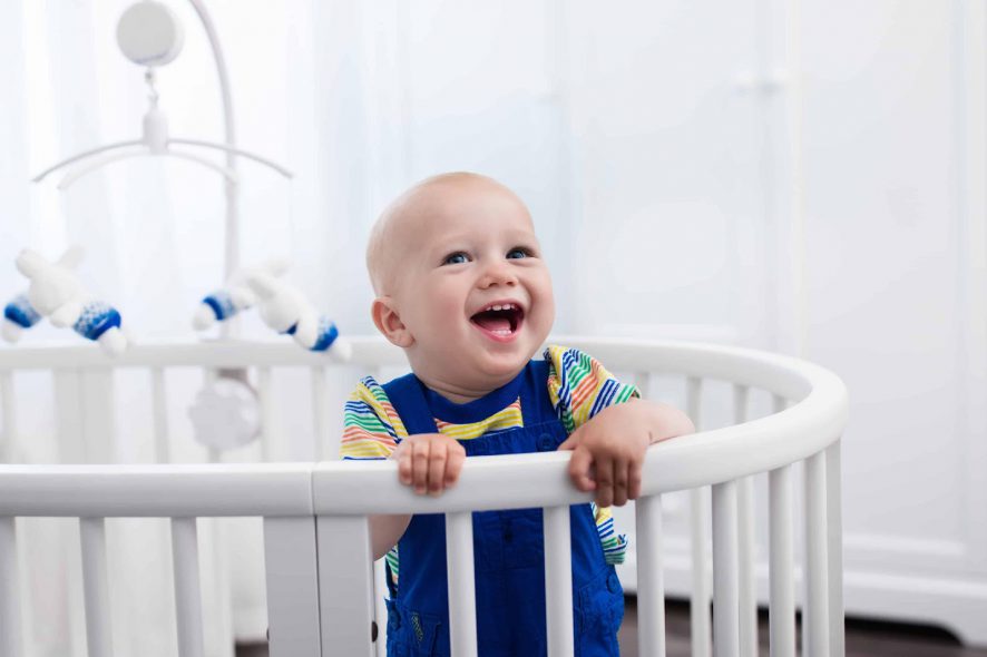 baby boy in blue on an oval crib
