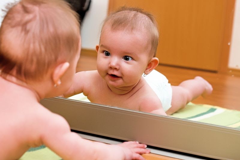 baby care play mat sizes - baby staring at their reflection in the mirror while on a mat