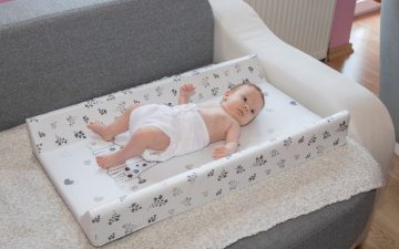 baby changing pad - A baby lying down on a changing pad with leaves printed on it