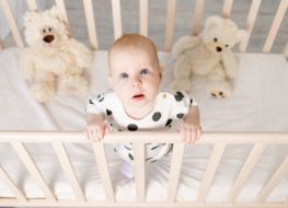 baby crib bedding - baby standing and holding on a crib rail