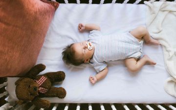 baby sleeping comfortable on a crib with mattress