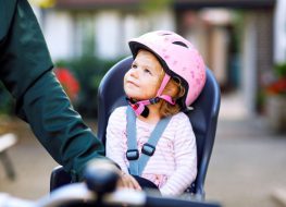 toddler bike seat - little girl on a bike seat with a pink helmet