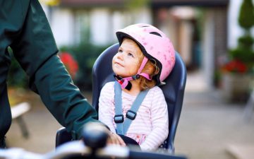 toddler bike seat - little girl on a bike seat with a pink helmet