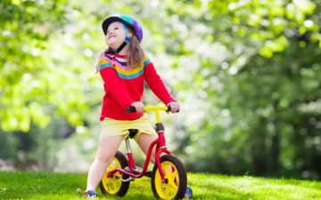 toddler girl bike - Parent guiding girl toddler on a balance bike
