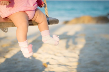 baby on the beach wearing pink baby girl socks on the swing