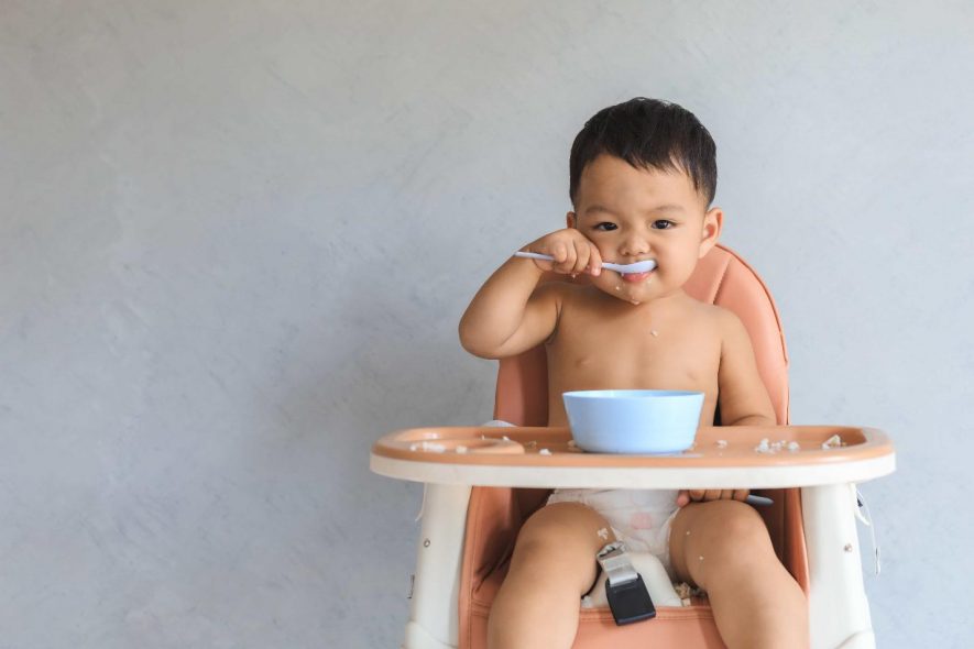 baby boy eating in a high chair 
