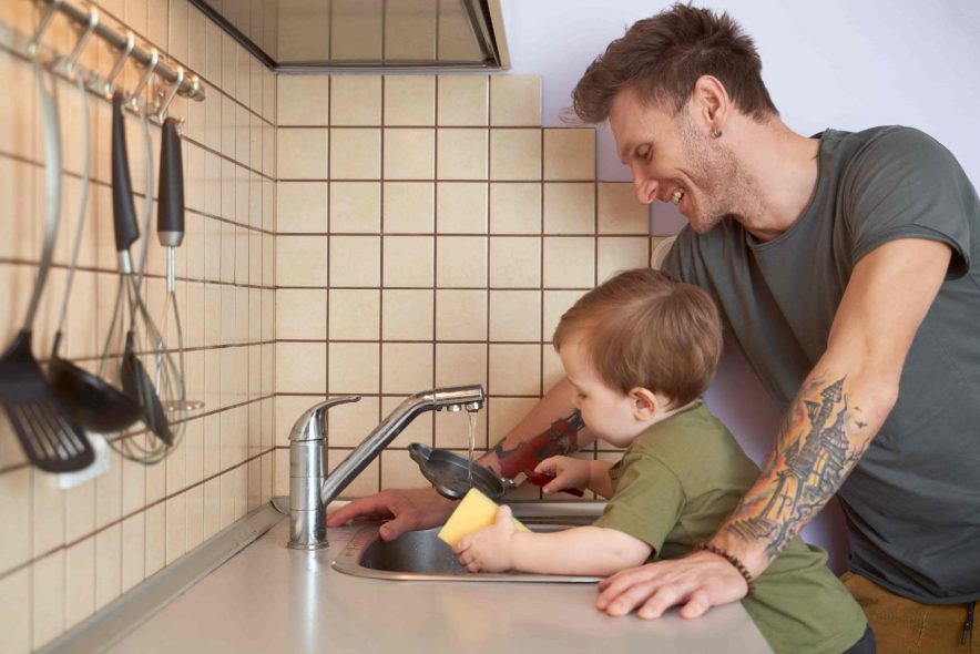 father teaching his son how to wash dishes 