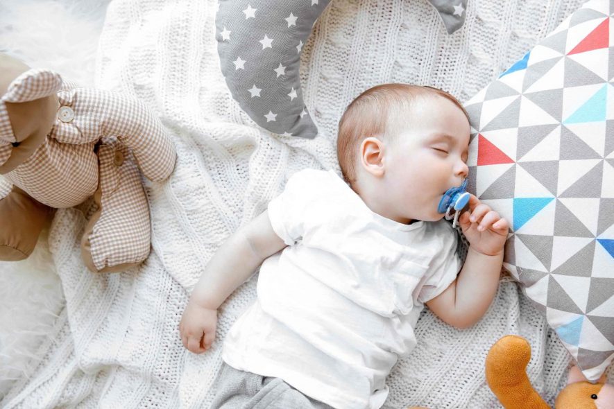 sleeping baby with pacifier and stuffed toys