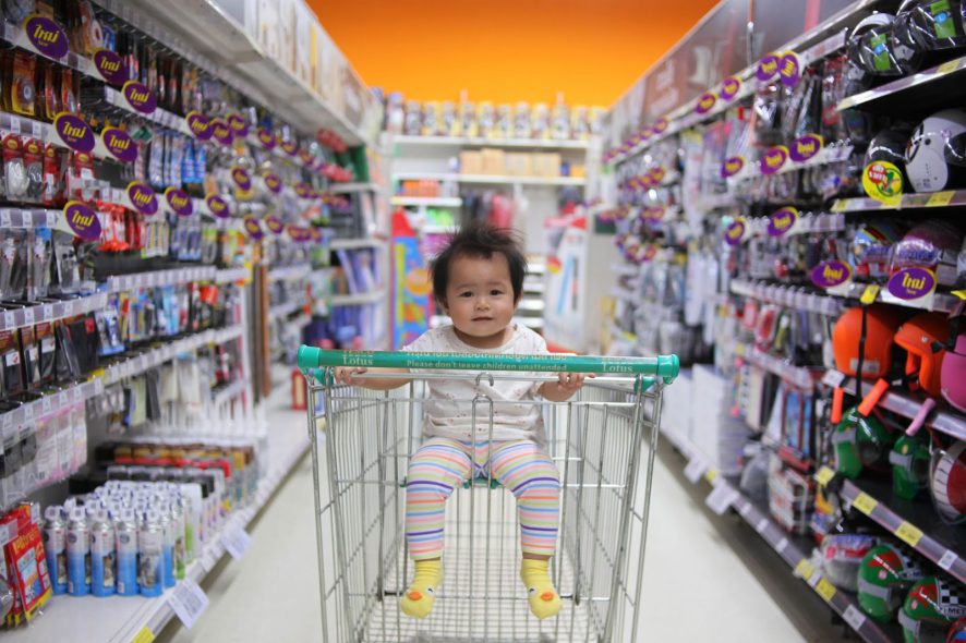 babysitting on the shopping card in the middle of the supermarket aisle