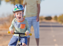 toddler push bike – little boy riding a push bike with his dad