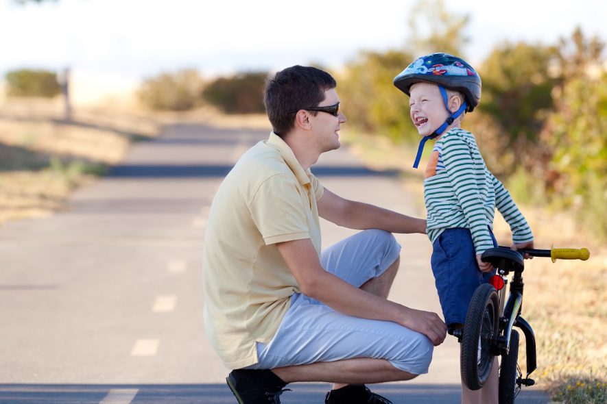 toddler push bike-1 – little boy having fun with his dad while learning to ride a push bike