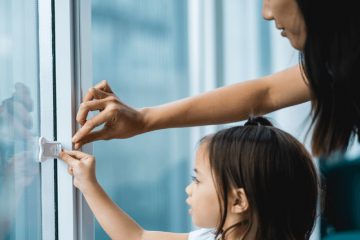 mother and her child using the sliding door lock for toddlers
