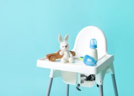 foldable high chair - white baby chair on blue background with toys and a baby bottle