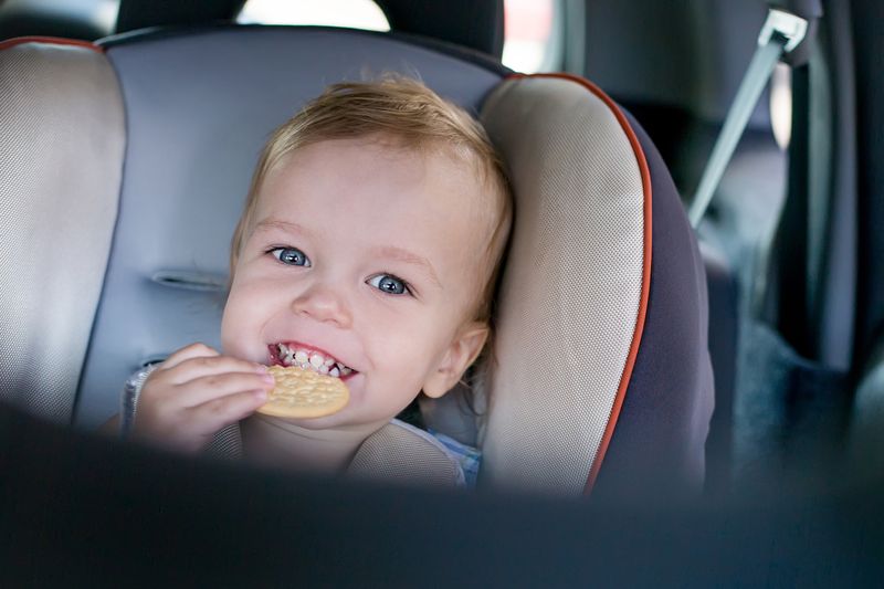 foldable high chair travel - toddler eating a cookie on a car seat 