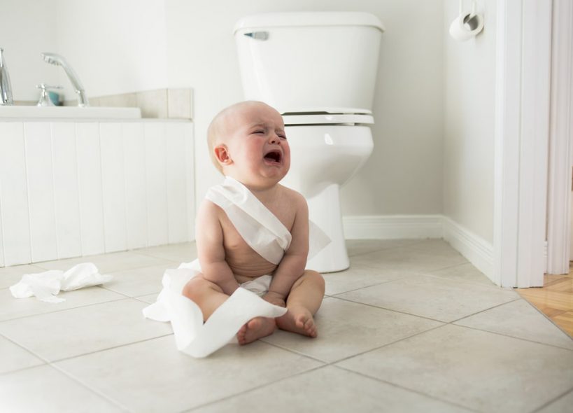 A crying baby near the big toilet