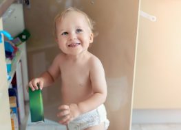 cabinet door locks - a toddler holding a green can from the kitchen cabinet