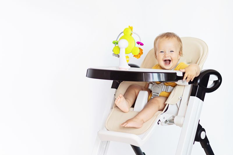 baby high chair - happy baby on a white high chair with a suction cup toy