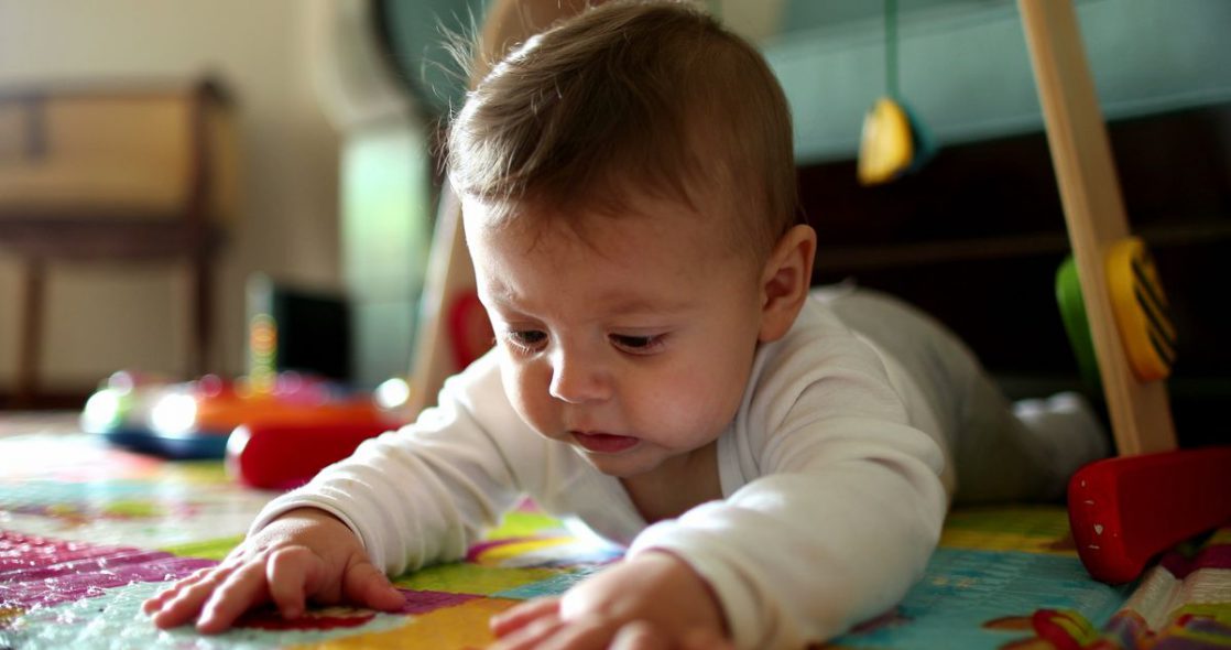 baby playmat - a baby on their tummy touching a play mat