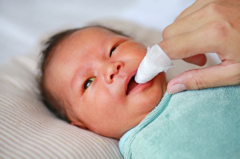 baby tongue cleaner - A finger with a soft cloth wrapped around it is used to clean a baby’s mouth and tongue