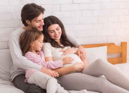 2nd baby must haves - family of three looking fondly at pregnant mom’s stomach