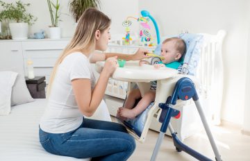 a mom feeding her infant in a high chair