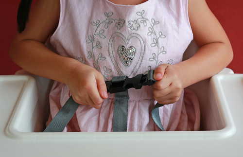 close up of a child holding a high chair's safety harness