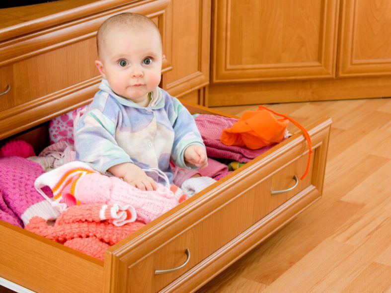 Best baby proofing products - A baby sits in an open drawer filled with clothes