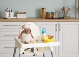 a toddler chair with food and toy in the kitchen