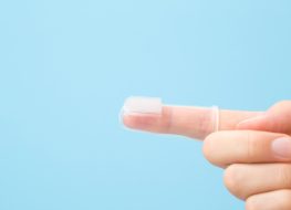 baby finger toothbrush inserted to an adult’s index finger.