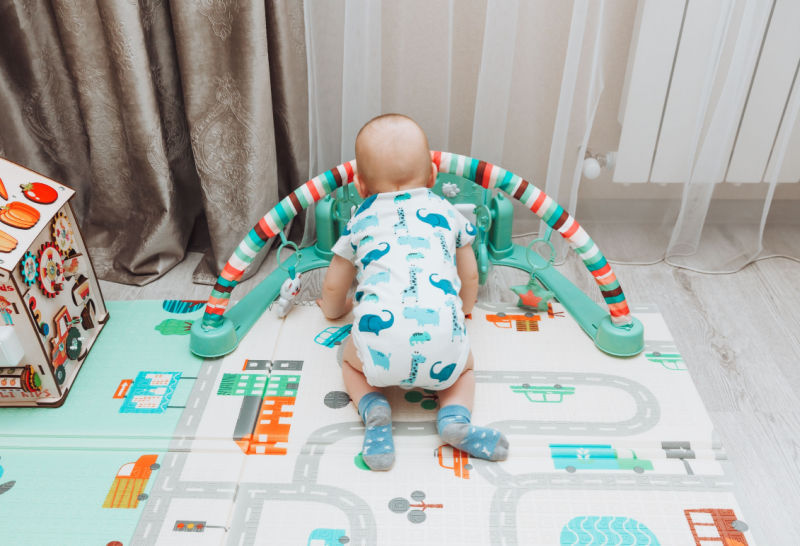 Baby playing on foam playmats with baby activity gym