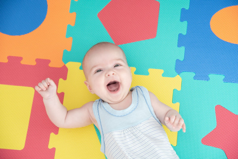 Smiling baby lying on top of foam playmats