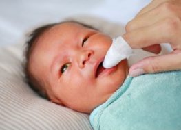 newborn tongue cleaner - baby's mouth being cleaned with gauze