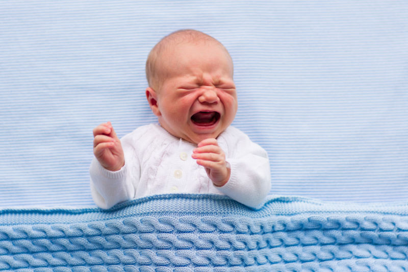 Baby crying on blue bedding