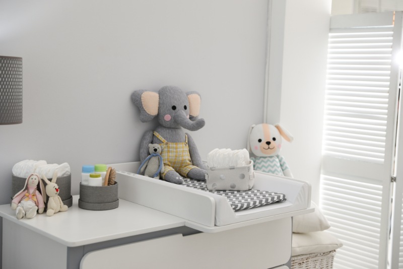 shot showing a changing table with a gray and white changing pad and stuffed toys