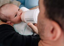 does a newborn need bibs - a baby feeding on a bottle