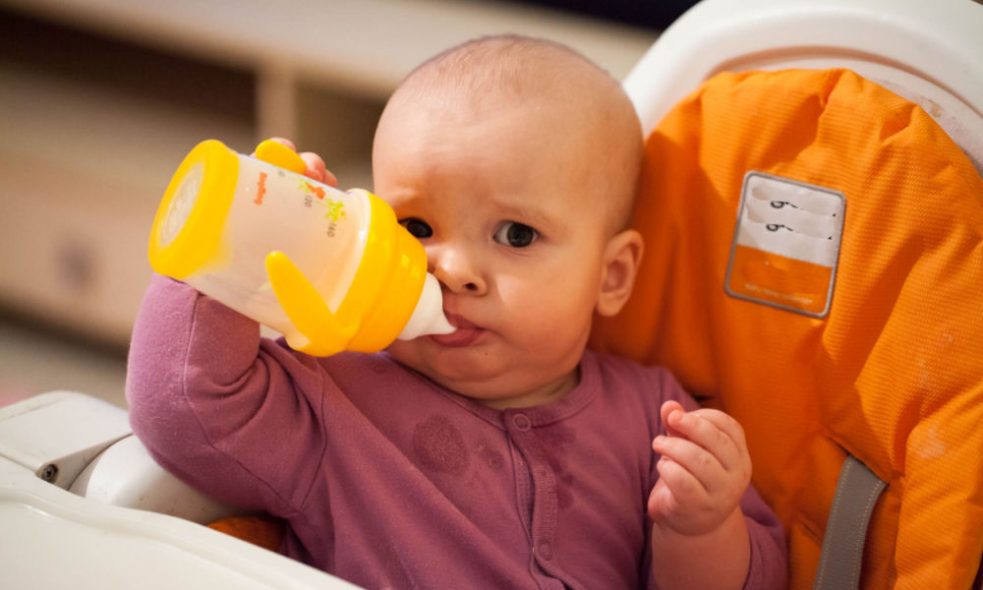 A baby expertly holding a sippy cup with one hand.