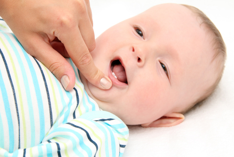 a baby smiling and showing their teeth with a hand checking their mouth