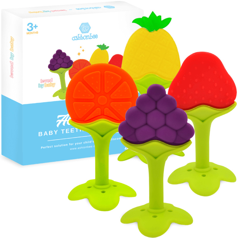 four fruit shaped baby teethers with a box. the teethers are in the shape of an orange, a grape, a strawberry, and a pineapple.