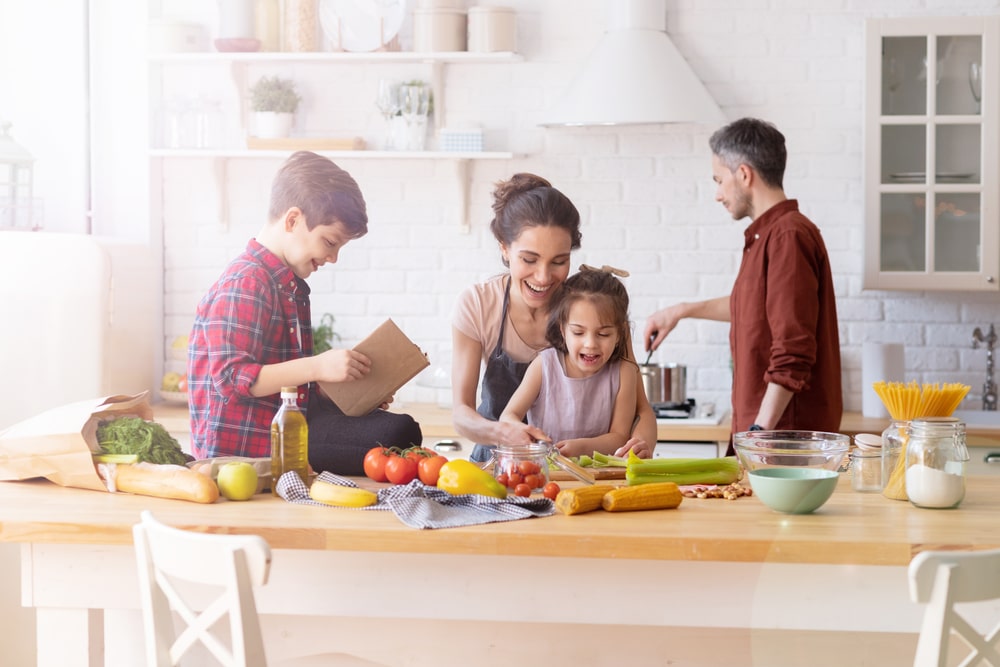 a family with a mom, dad, a son, and a daughter, cooking healthily in a kitchen