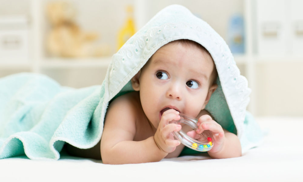 An infant biting a teething ring.
