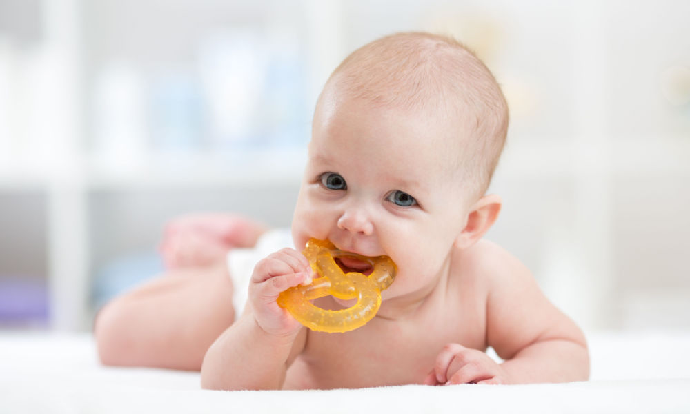 A baby gnawing on a pretzel-shaped teether.