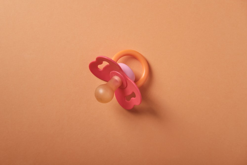 a pink and orange baby pacifier on an orange background