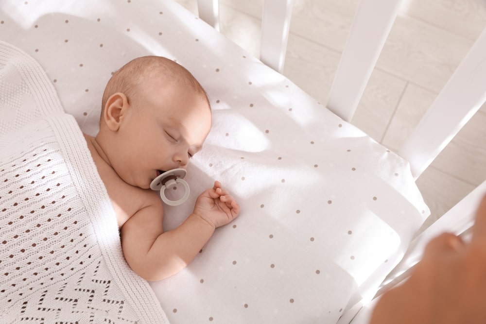 baby in a crib sleeping with a pacifier